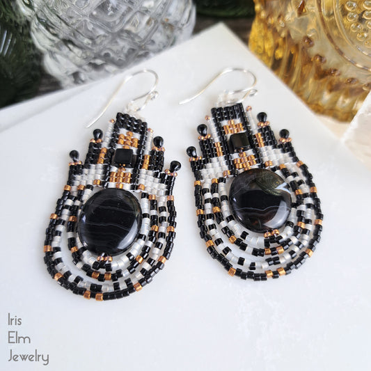 Pair of beaded black agate stone and seed bead earrings with black and gold accents on a white surface, with 'Iris Elm Jewelry' branding.