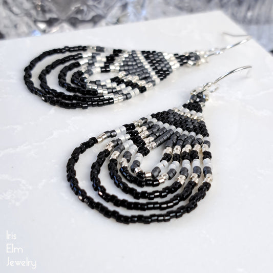 Black and white beaded teardrop seed bead earrings on a white surface with 'Iris Elm Jewelry' branding.