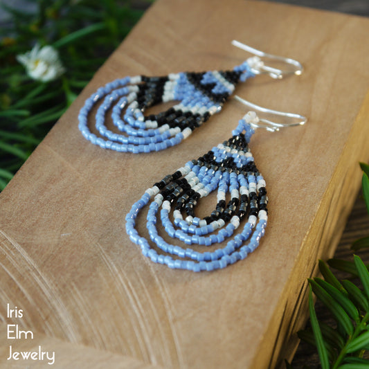 Light blue glass seed bead teardrop earrings on a wooden block with 'Iris Elm Jewelry' branding.