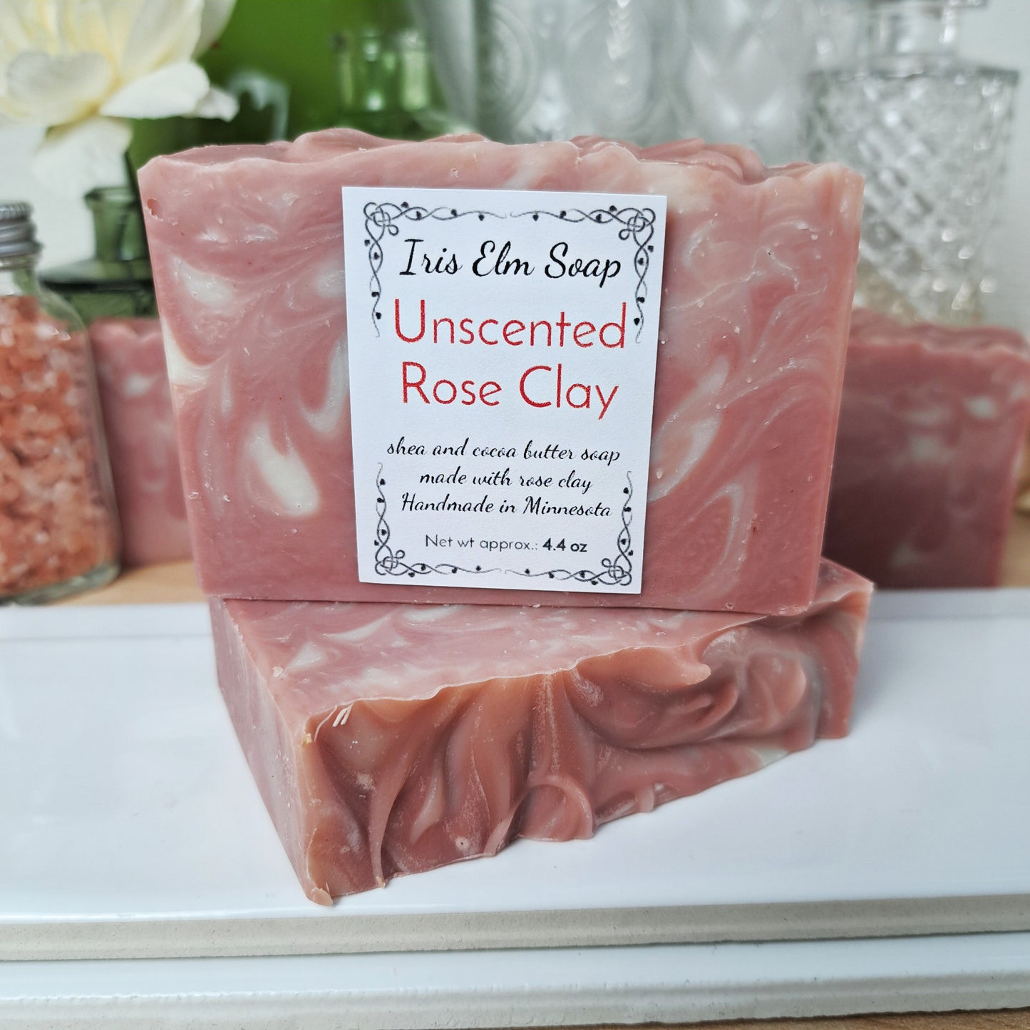 Pink rose clay unscented handmade soap bar with a Iris Elm Soap label on a white surface, with blurred background