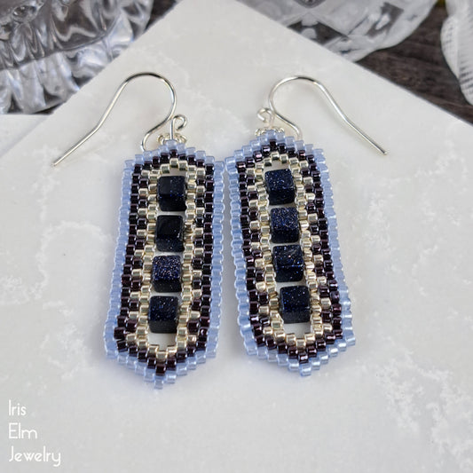 Beaded blue goldstone earrings on a white surface with 'Iris Elm Jewelry' branding.