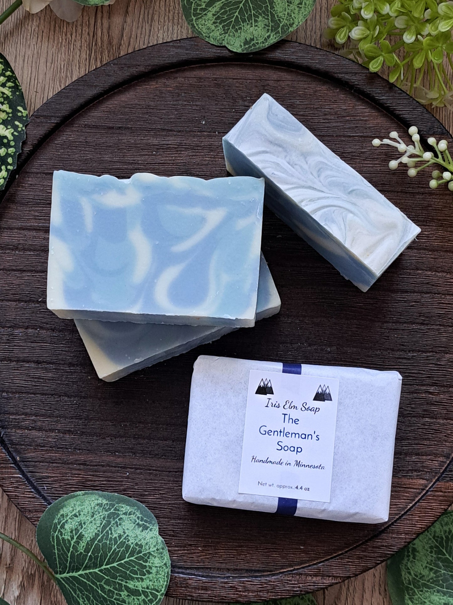 Three bars of the perfect gentlemen handmade soap on a wooden surface with greenery around