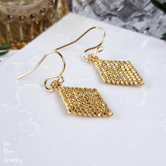 Gold geometric small diamond shaped earrings on a white surface with 'Iris Elm Jewelry' branding.