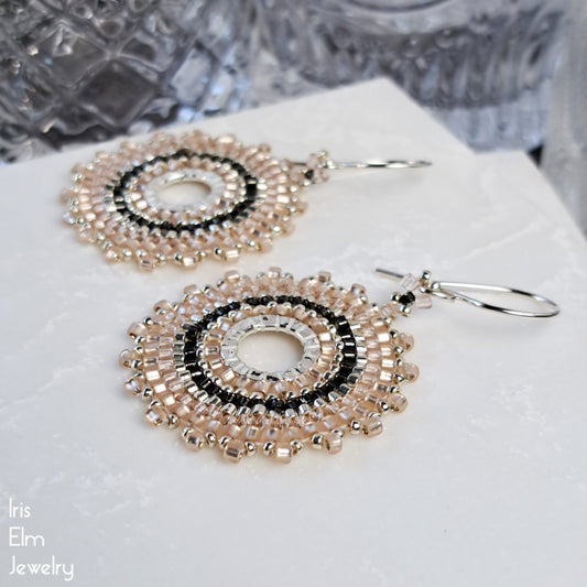 Pair of beaded pale pink woven glass seed bead hoop earrings on a white surface with 'Iris Elm Jewelry' branding.