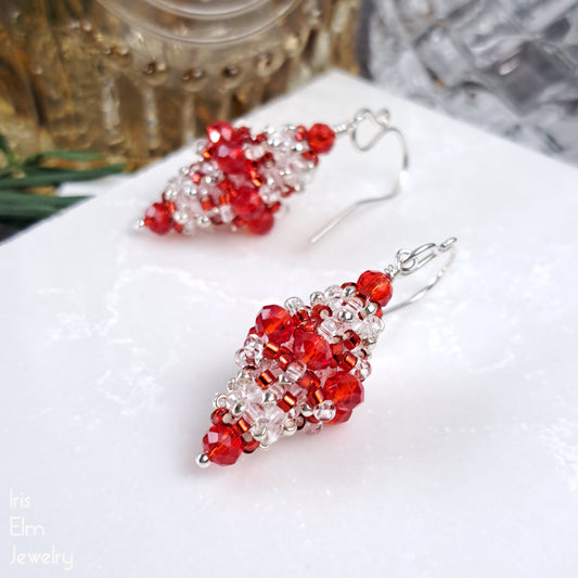 Red and clear glass beaded bead earrings on a white surface with a blurred background