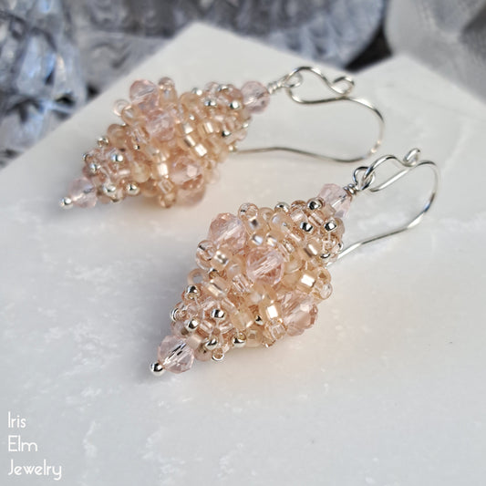 Pair of pale blush pink faceted glass beaded bead earrings on a white surface with 'Iris Elm Jewelry' branding.