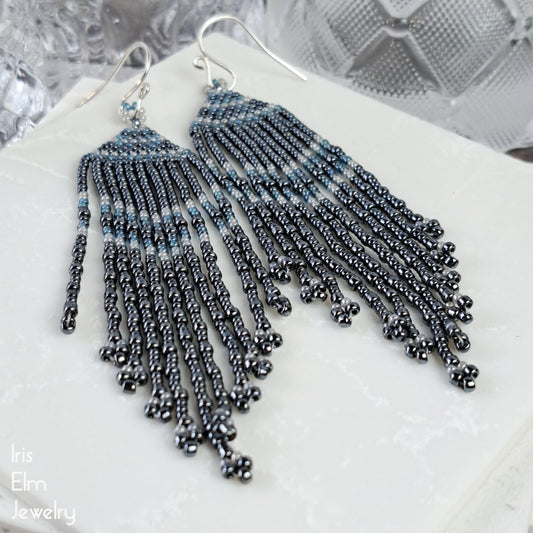 Beaded charcoal grey seed bead fringe earrings on a white surface with 'Iris Elm Jewelry' branding.
