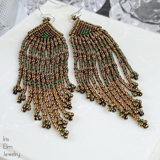 Pair of beaded brown seed bead fringe earrings on a white surface with 'Iris Elm Jewelry' branding.
