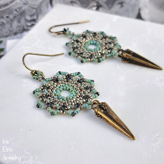 green glass Beaded mandala earrings with brass spike details on a white surface, featuring 'Iris Elm Jewelry' branding.