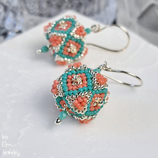 Beaded seed bead 3d cube earrings with turquoise and coral colors on a white surface