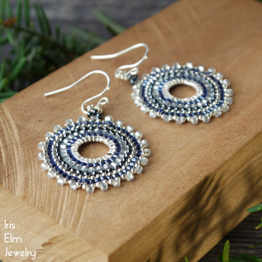 Pair of blue seed bead beaded hoop earrings on a wooden surface with 'Iris Elm Jewelry' branding.
