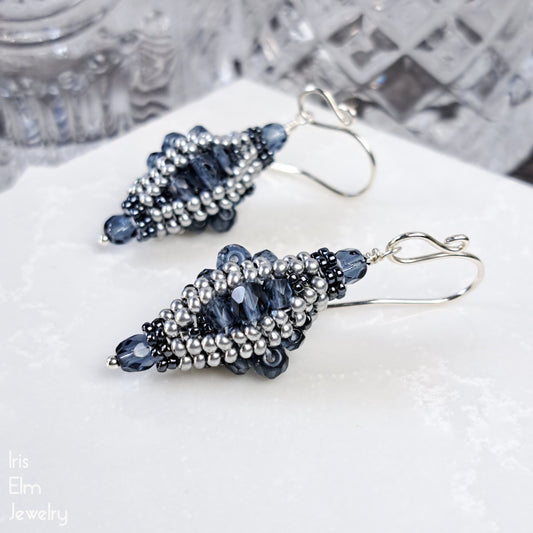 Beaded blue Czech glass lantern earrings on a white surface with a blurred background