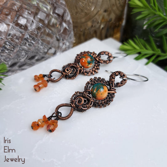 Pair of copper and stone ocean jade and carnelian wire wrapped earrings on a white surface with 'Iris Elm Jewelry' branding.