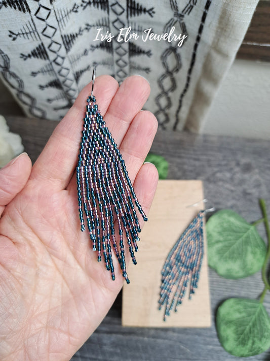 Hand holding a beaded forest green and pink seed bead fringe art deco earring with 'Iris Elm Jewelry' branding.