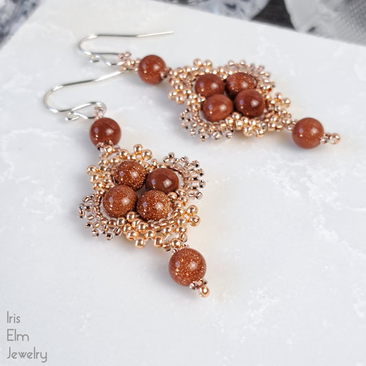 Beaded earrings with brown goldstone and copper glass seed beads on a white surface, branded 'Iris Elm Jewelry'.