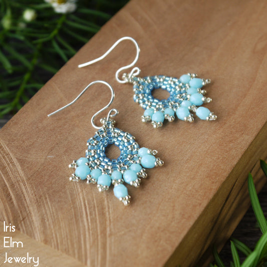 Pair of light blue beaded Czech glass earrings on a wooden surface with 'Iris Elm Jewelry' branding.