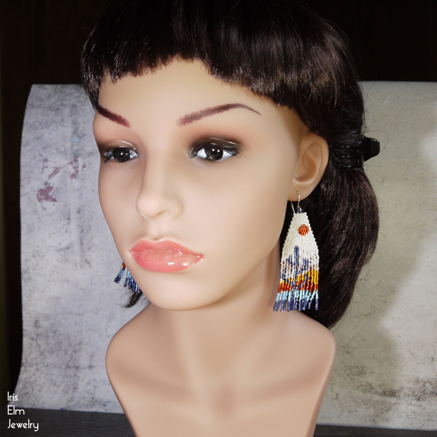 Mannequin head with colorful beaded cactus fringe earrings on a neutral background
