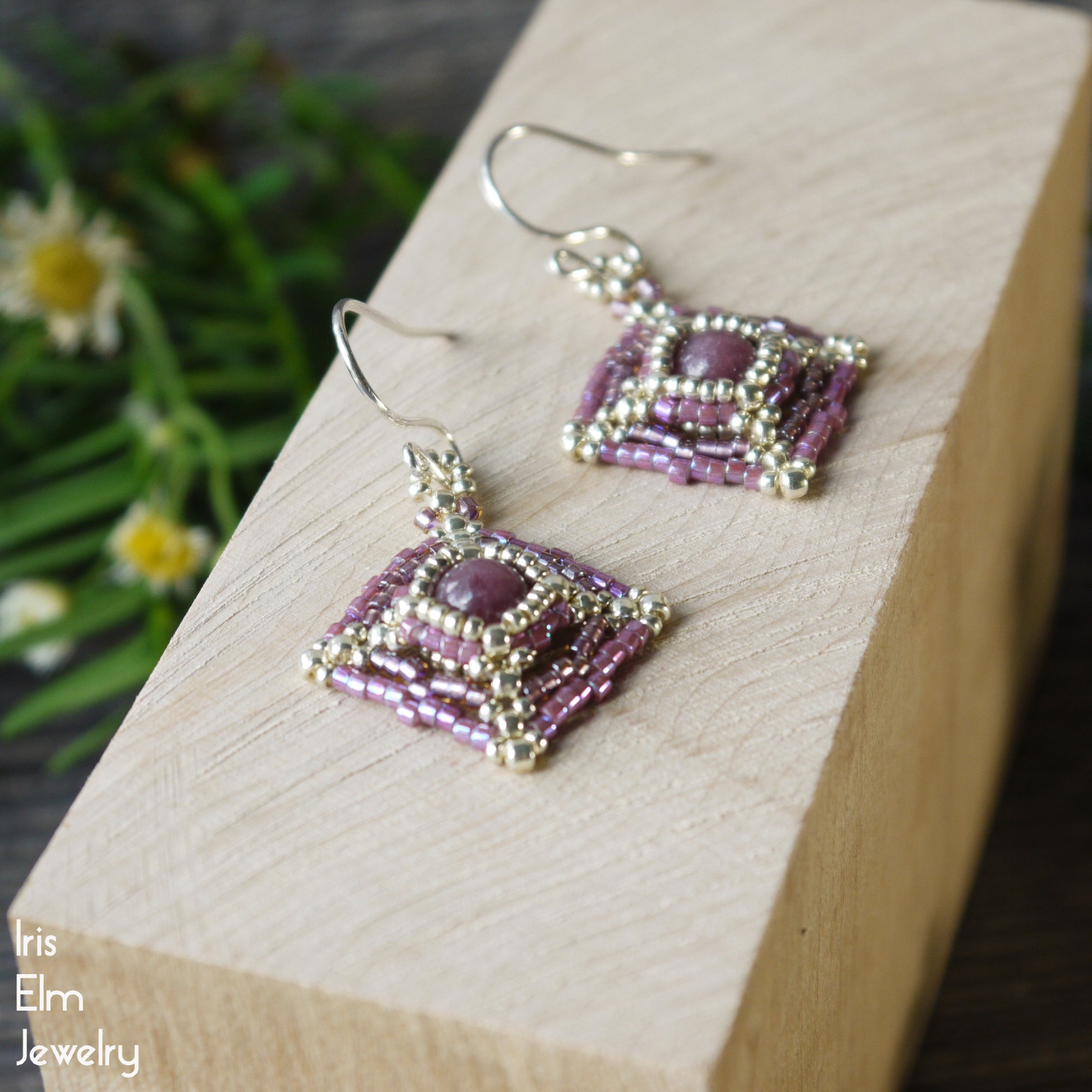 Pair of lepidolite stone and seed bead beaded earrings with sterling silver ear wires on a wooden block with a natural background
