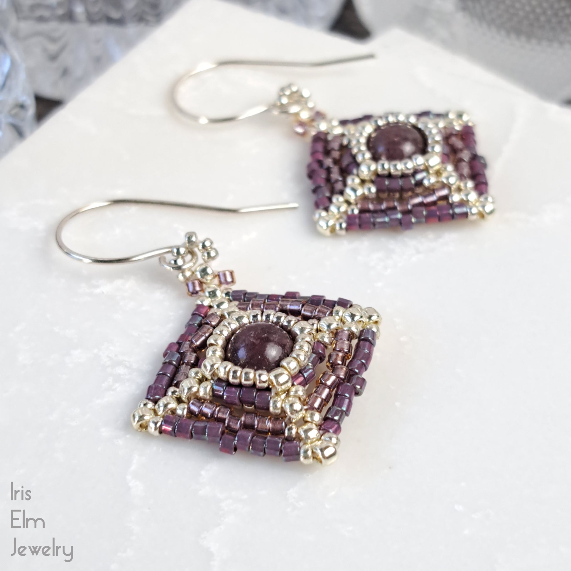 Pair of pink purple lepidolite beadwork earrings on a white surface with 'Iris Elm Jewelry' branding.
