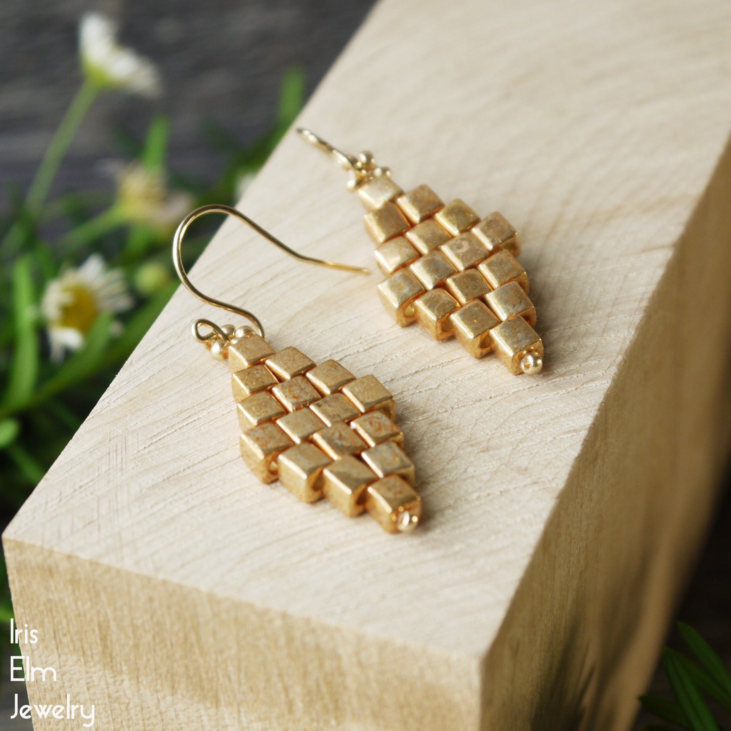 handmade Gold woven glass earrings on a wooden block with a natural background