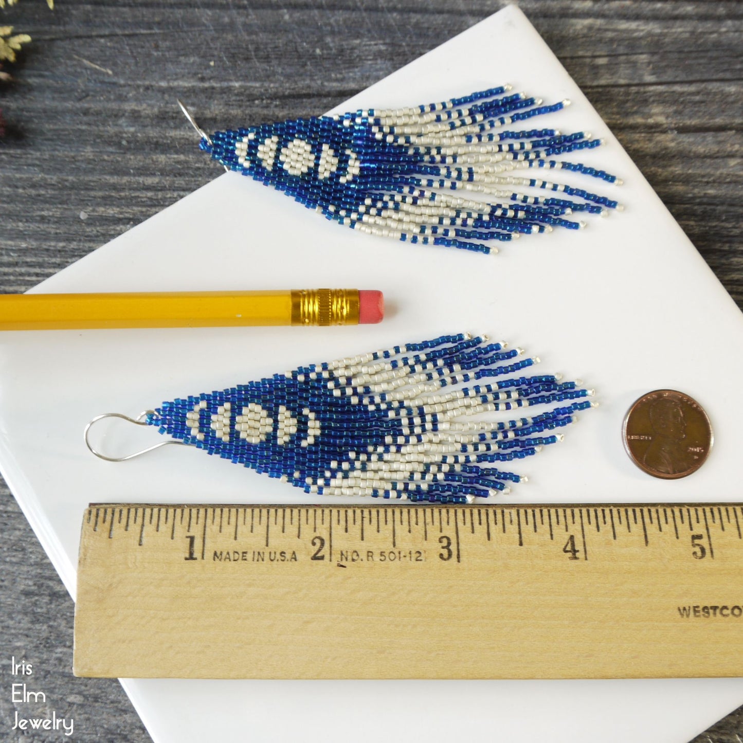 4.25 inch long Blue and white beaded moon phase earrings on a white surface with a ruler for scale.