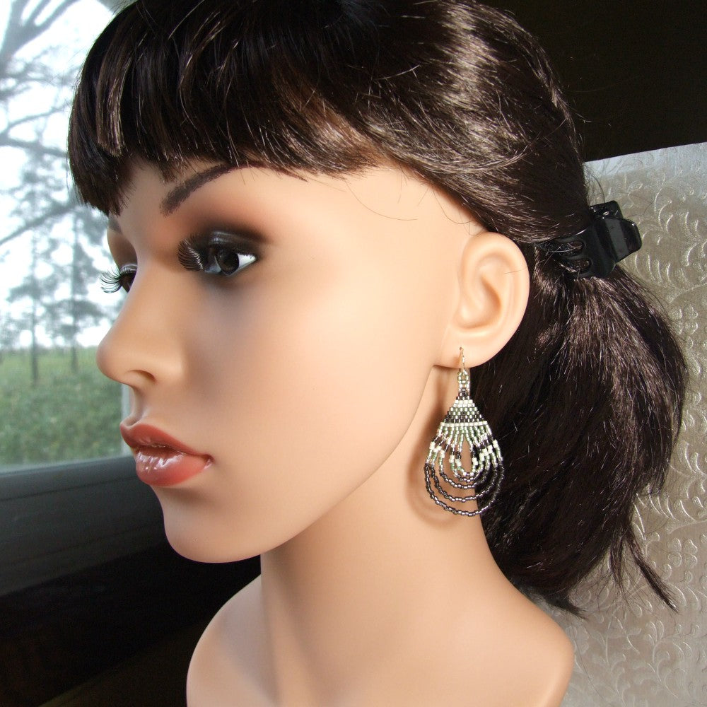 Mannequin head with dark hair styled in a ponytail and wearing teardrop earrings.