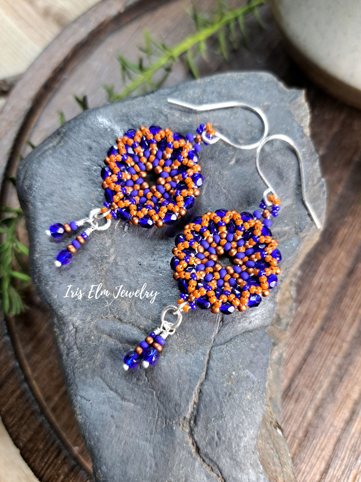 cobalt blue and burnt orange handmade beadwork Czech glass hoop wreath beaded earrings by Iris Elm Jewelry on rocky surface