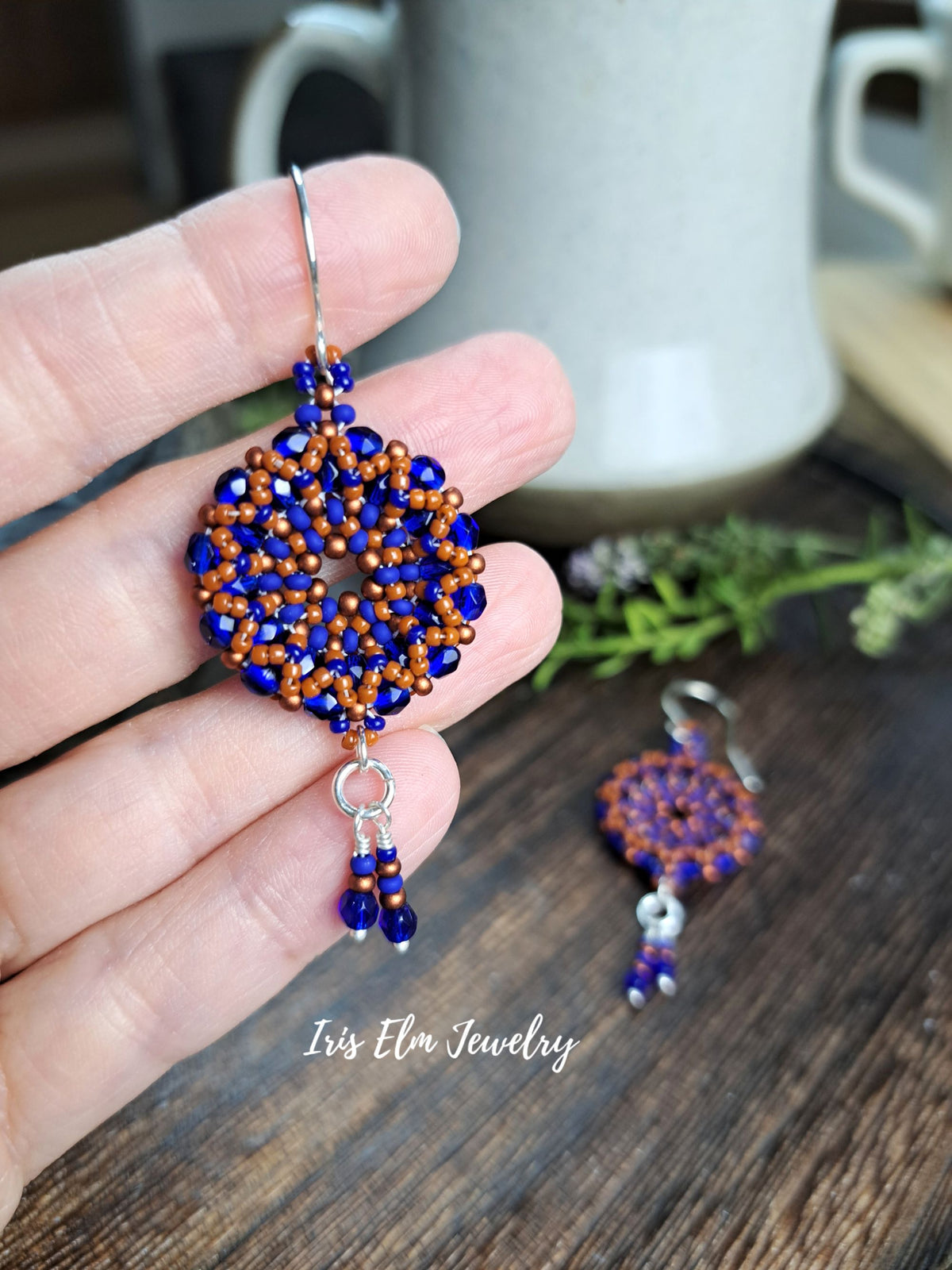 cobalt blue and burnt orange handmade beadwork Czech glass hoop wreath beaded earrings by Iris Elm Jewelry held in hand
