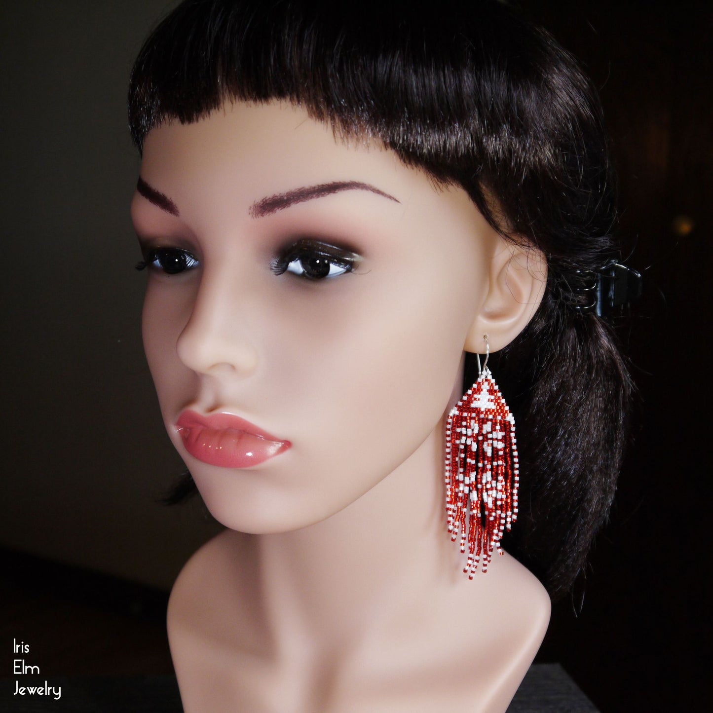 Mannequin head with red beaded earrings on a dark background
