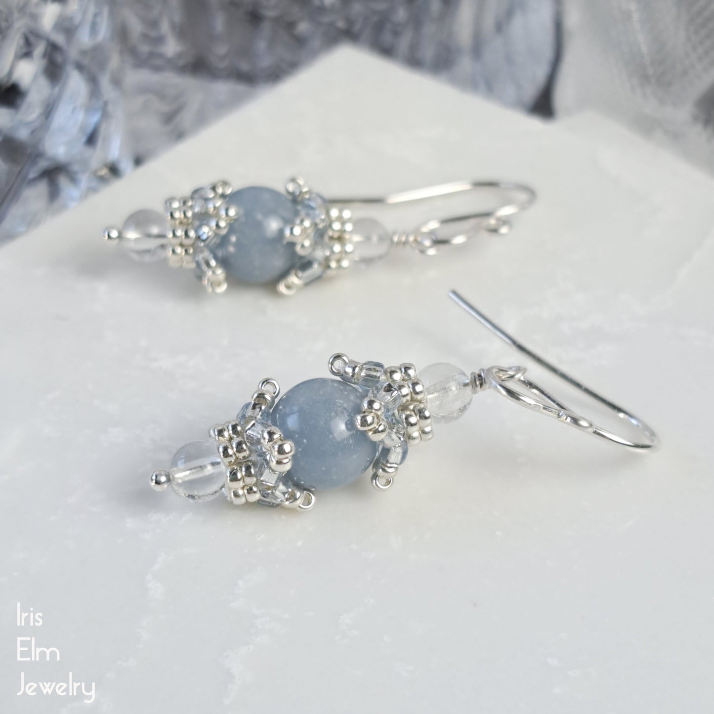 beadwork earrings with blue angelite and quartz gemstones on a white surface, branded 'Iris Elm Jewelry'.