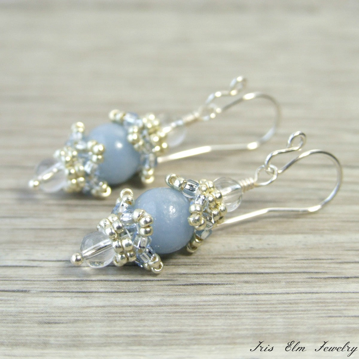 Pair of beaded sterling silver earrings with blue angelite beads and clear crystals on a wooden surface
