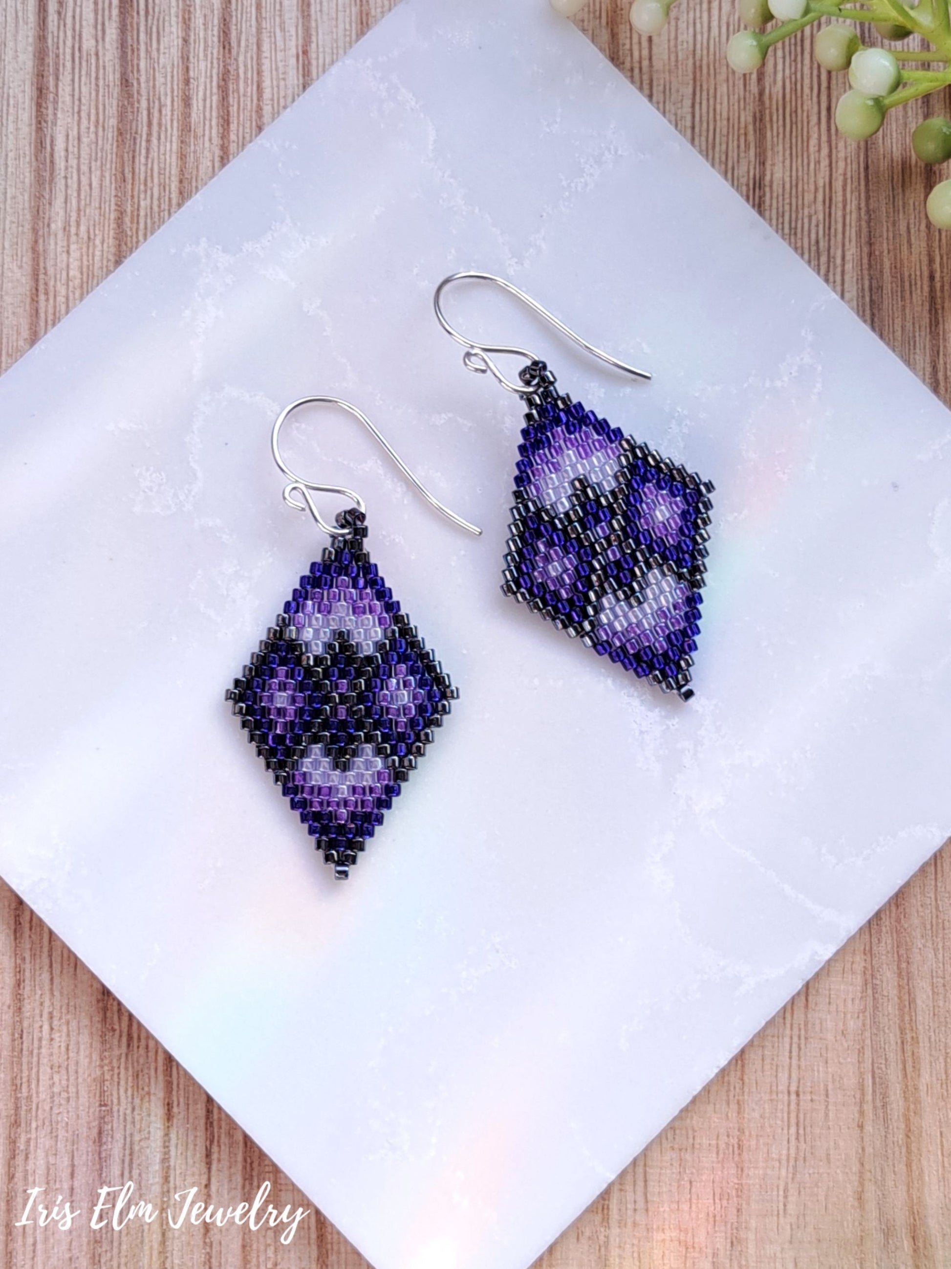 purple geometric diamond glass seed bead handmade beadwork earrings on white marble surface with Iris Elm Jewelry branding