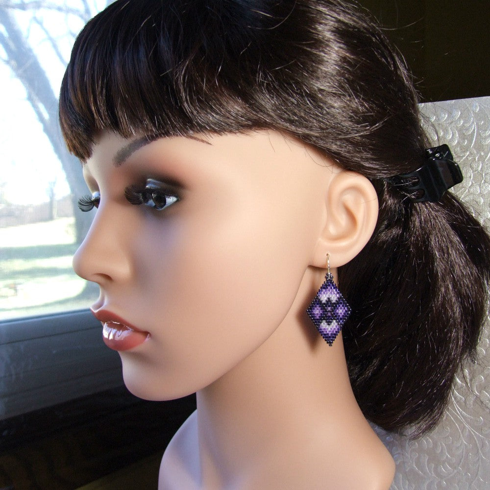 Mannequin head with dark hair and purple beaded earrings, blurred background