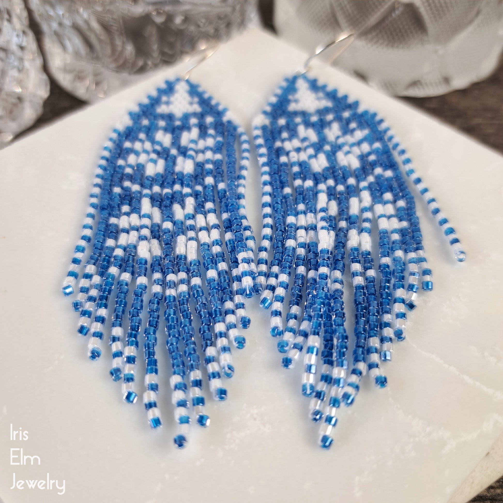 Blue and white beaded long fringe earrings on a white surface with 'Iris Elm Jewelry' branding.