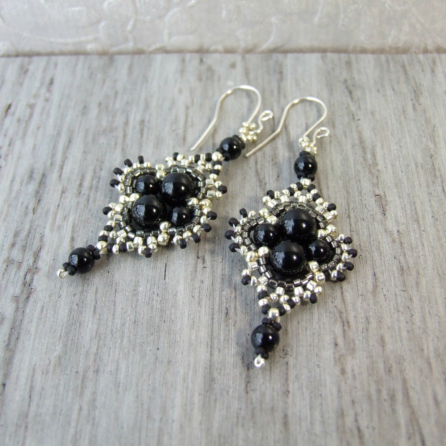 Black onyx stone beaded earrings with silver and grey seed bead accents on a light wooden surface