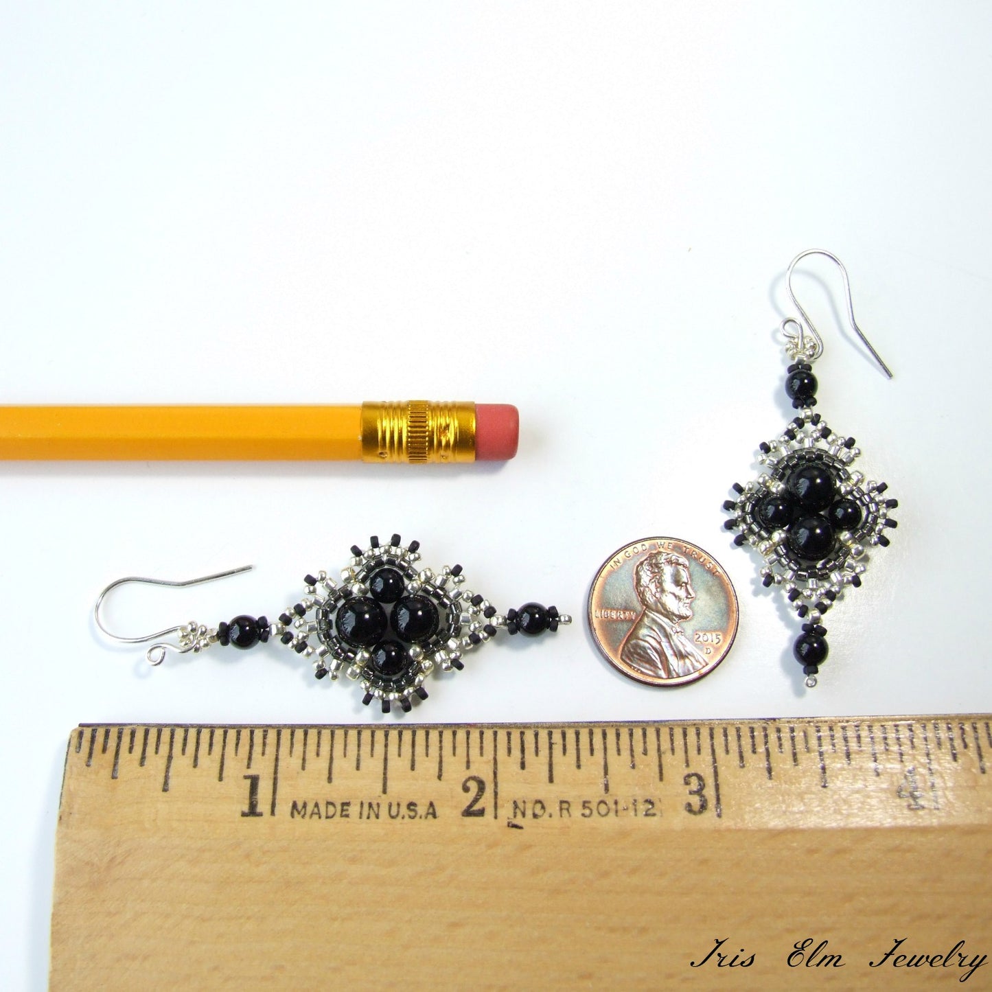 2 and 3/8 inches long Black and silver earrings with a pencil and penny for scale on a white background