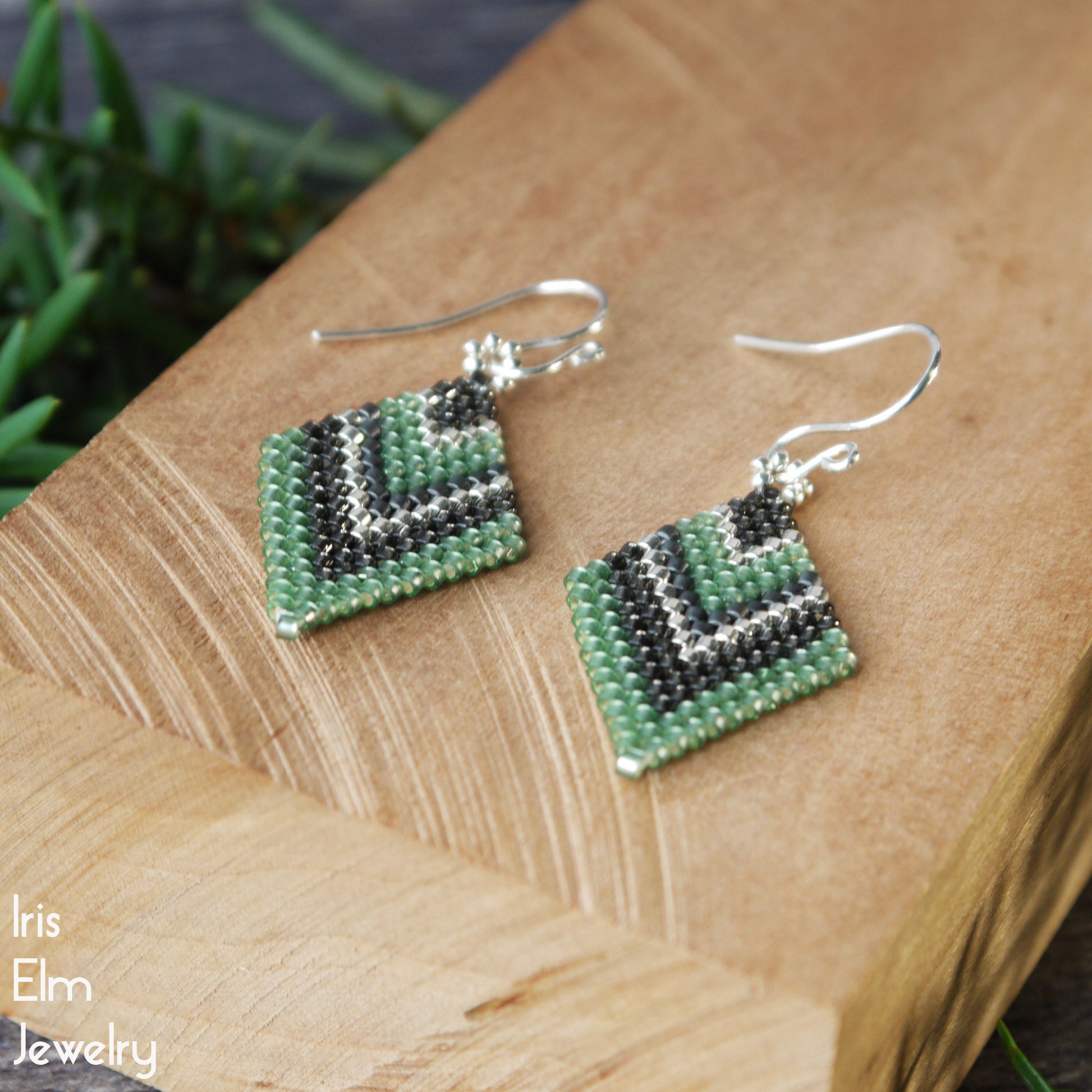 green and grey diamond shape seed bead beaded earrings on a wooden surface with 'Iris Elm Jewelry' branding.