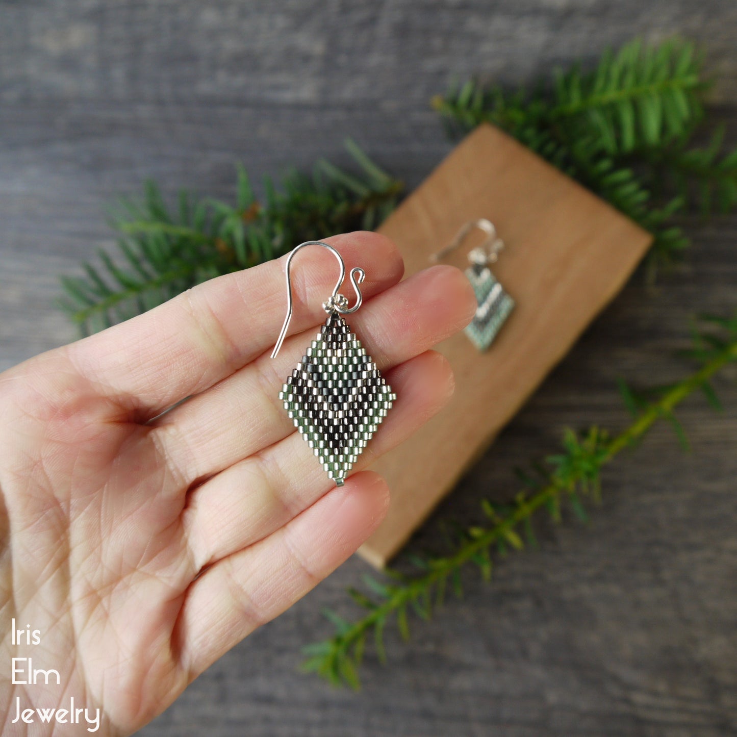 light green seed bead brick stitch earrings held in a hand with a natural background