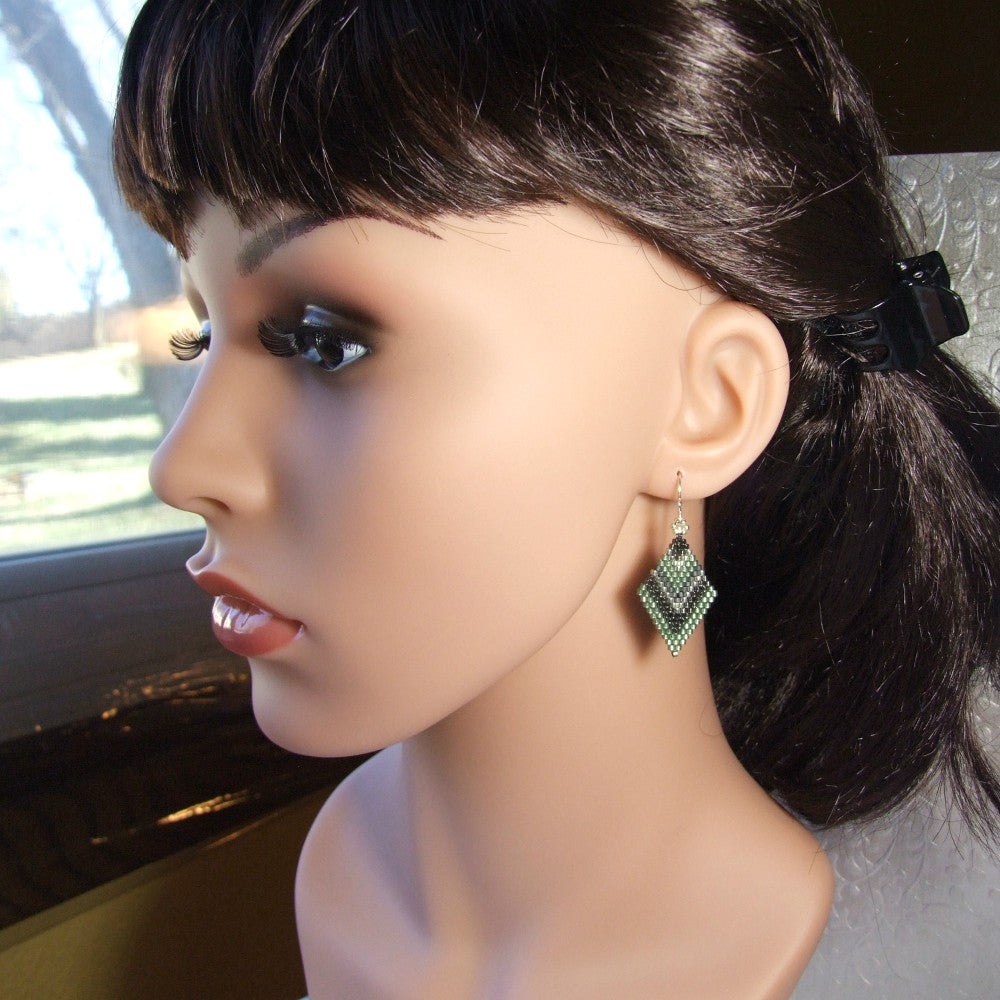 Mannequin head with dark hair and green earrings.