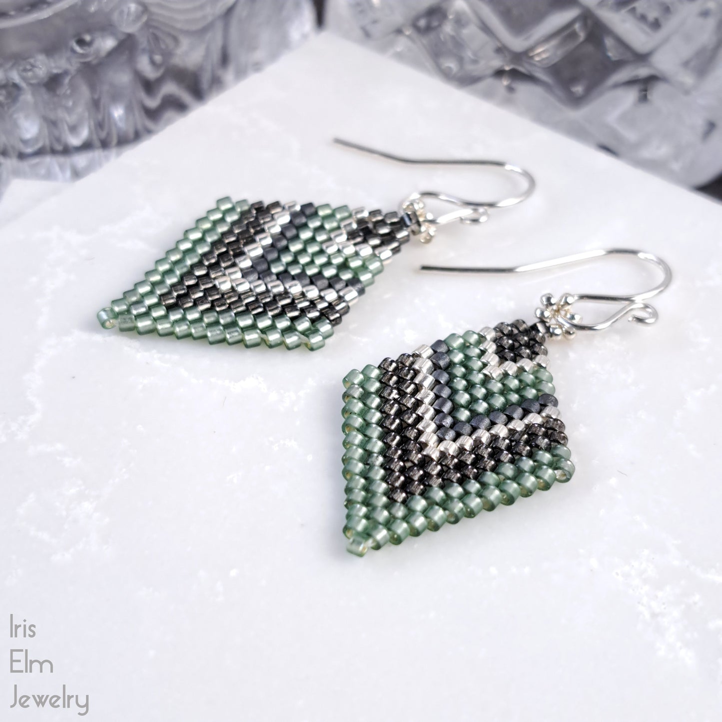 Pair of beaded light green diamond seed bead earrings on a white surface with 'Iris Elm Jewelry' branding.