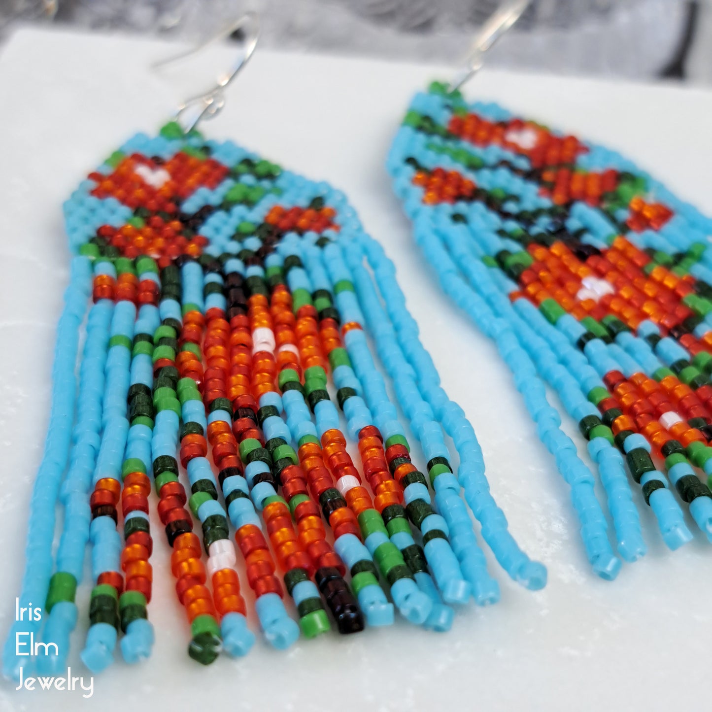 Colorful beaded earrings on a white surface with 'Iris Elm Jewelry' branding.