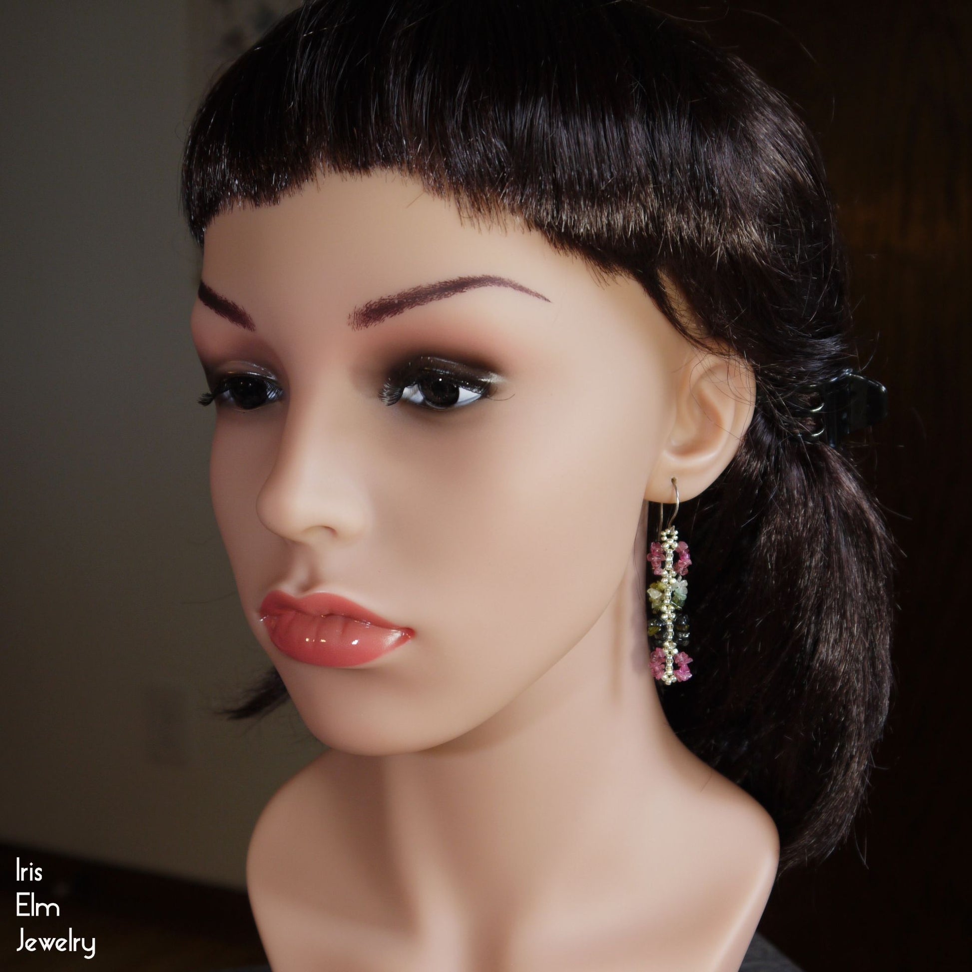 Mannequin head with black hair and colorful tourmaline earrings, featuring 'Iris Elm Jewelry' branding.