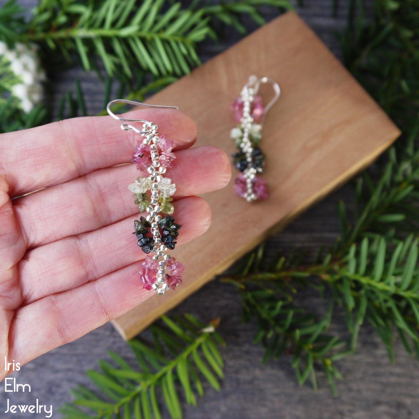 Colorful beaded handmade rainbow tourmaline earrings held in a hand with a natural background