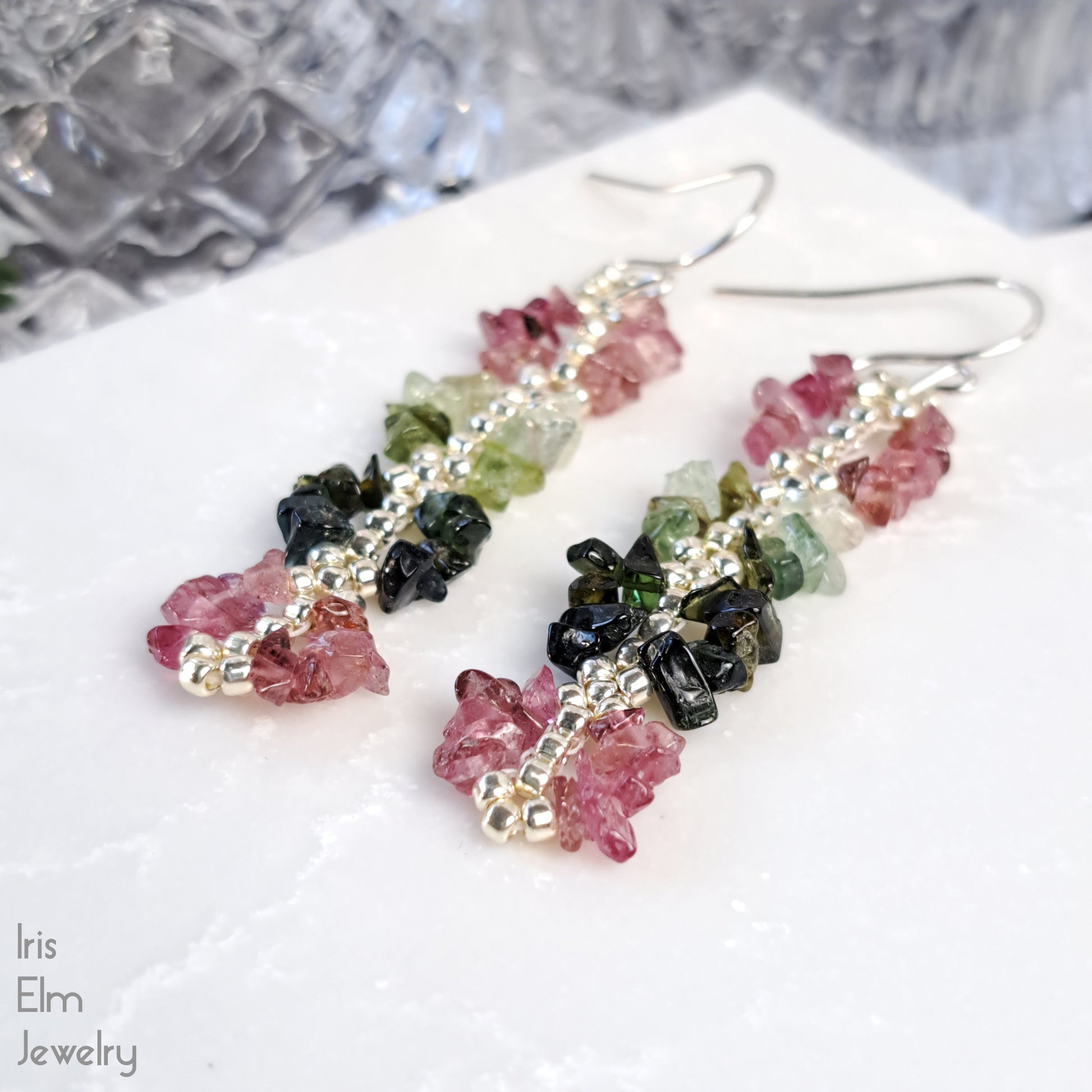 Multicolored rainbow tourmaline gemstone earrings on a white surface with 'Iris Elm Jewelry' branding.