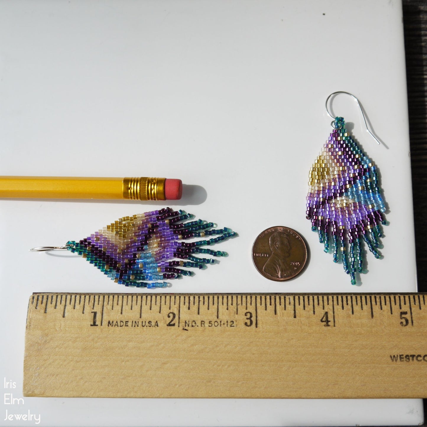 2.75 inch long Beaded earrings next to a pencil and coin on a white background with a ruler for scale.