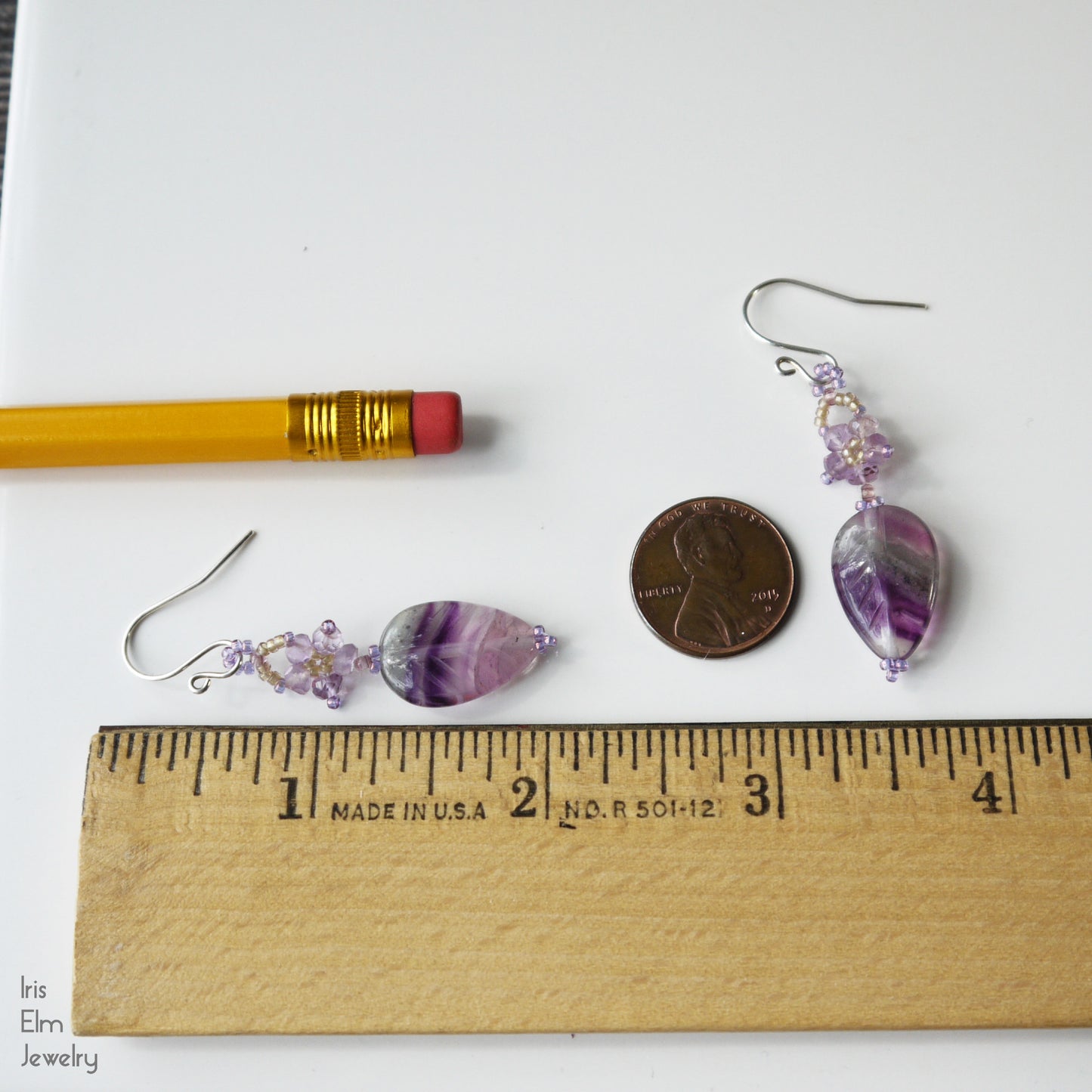 2 inch long Purple leaf earrings with floral elements on a white background with a ruler for scale.