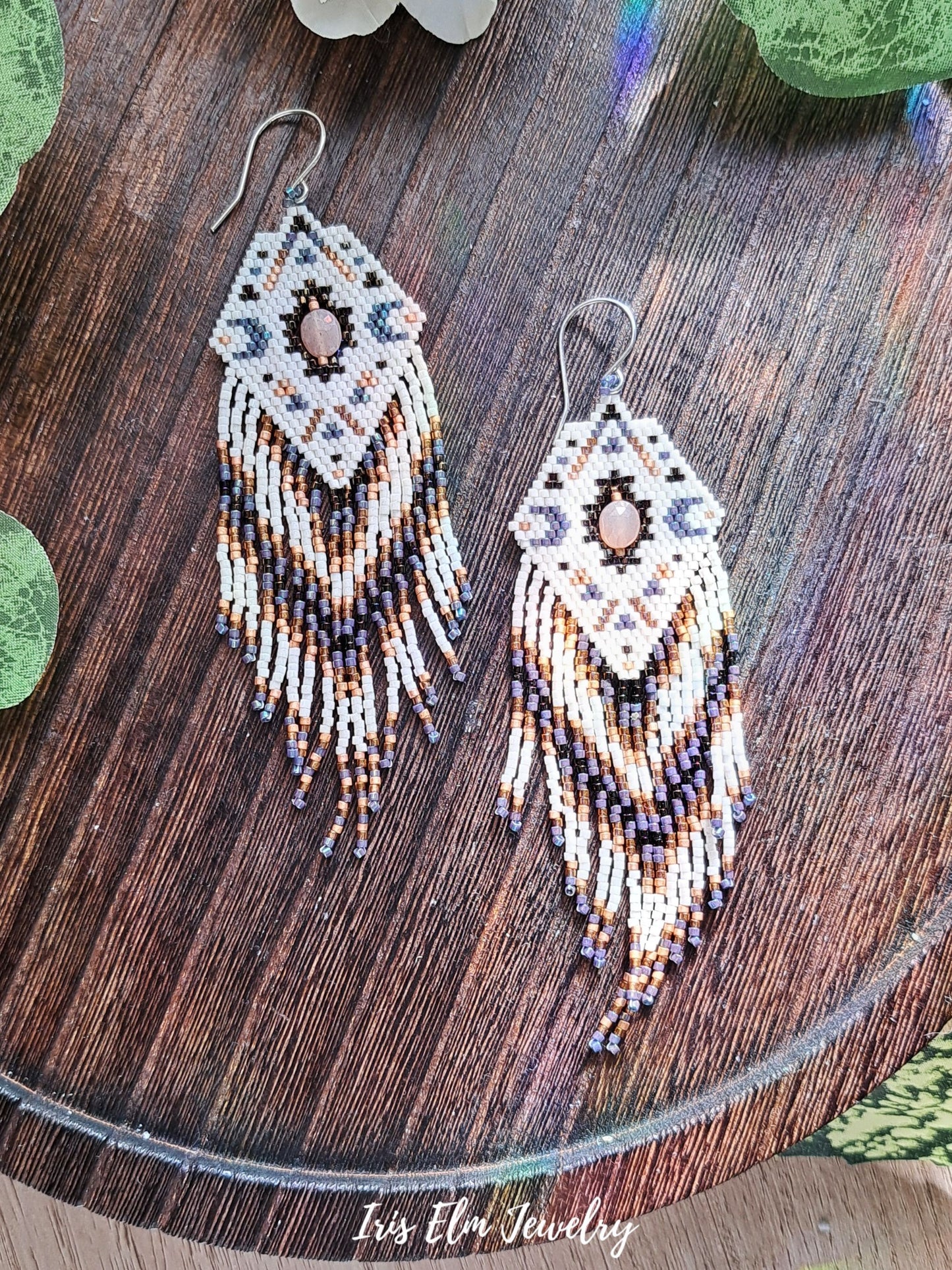 Beaded diamond fringe statement earrings with moonstone on a wooden surface with 'Iris Elm Jewelry' branding.