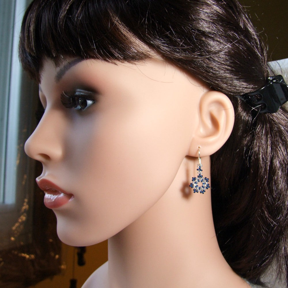 Mannequin head with dark hair and a decorative snowflake earring on a blurred background