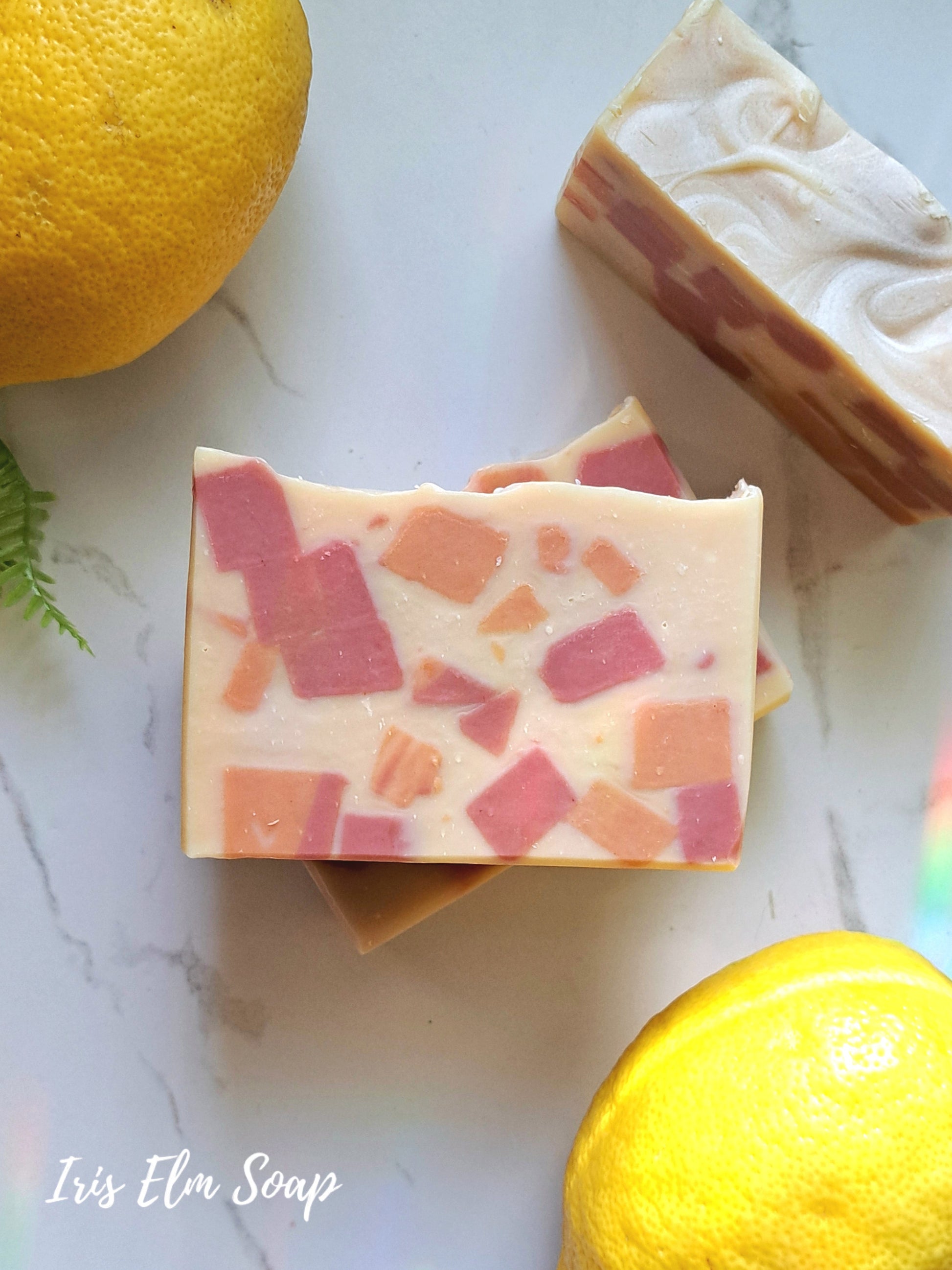 Two sweet lemon tea handmade soap bars with a mosaic pattern and lemons on a marble surface, featuring 'Iris Elm Soap'.
