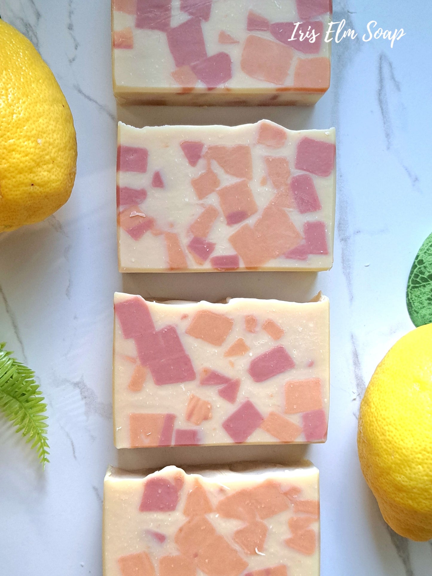 Terrazzo-patterned sweet lemon tea handmade soap bars with pink and orange specks on a white surface with lemons and green leaves.